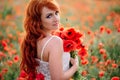 Beautiful young red-haired woman in poppy field holding a bouquet of poppies Royalty Free Stock Photo