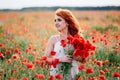 Beautiful young red-haired woman in poppy field holding a bouquet of poppies Royalty Free Stock Photo