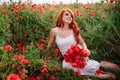 Beautiful young red-haired woman in poppy field holding a bouquet of poppies Royalty Free Stock Photo