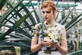beautiful young redhead bride holding wedding bouquet and looking away in botanical Royalty Free Stock Photo