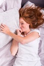 Beautiful, young, redheaded woman is hiding behind the pillow