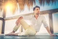 Beautiful young relaxed man in a small wooden deck. Strong summer warm light