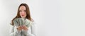 beautiful young rich girl waving a pack of 100 dollar bills like a fan, making eyes smiling on a white background, hair Royalty Free Stock Photo