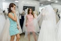 Beautiful young sales woman showing wedding dress to a customer