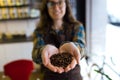 Beautiful young saleswoman holding coffee grains in organic shop.