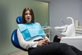 Beautiful young scared patient woman sitting in dental chair during examination at dental office looks frightened , healthcare