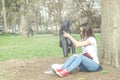 Beautiful young school or college girl with long hair, eyeglasses and black leather jacket sitting on the ground in the park readi Royalty Free Stock Photo