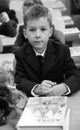 Beautiful young schoolboy sitting at wooden desk in school uniform during lesson