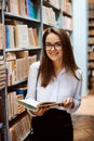 Brunette girl in glasses in white blouse and black skirt with a book