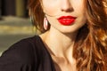 Beautiful young girl with makeup with enticing the big red lips and long hair in a Sunny summer day sitting on the street Royalty Free Stock Photo