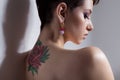 Beautiful young girl with short hair with tattoo on his back is against the wall with bare shoulders sad Royalty Free Stock Photo