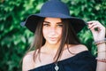 Beautiful young girl with swarthy skin and brunette with black hair dressed in a stylish black dress and hat on background of Royalty Free Stock Photo