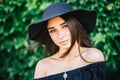 Beautiful young girl with swarthy skin and brunette with black hair dressed in a stylish black dress and hat on background of Royalty Free Stock Photo