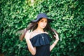 Beautiful young girl with swarthy skin and brunette with black hair dressed in a stylish black dress and hat on background of Royalty Free Stock Photo