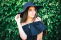 Beautiful young girl with swarthy skin and brunette with black hair dressed in a stylish black dress and hat on background of Royalty Free Stock Photo
