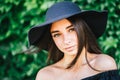 Beautiful young girl with swarthy skin and brunette with black hair dressed in a stylish black dress and hat on background of Royalty Free Stock Photo