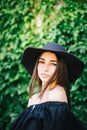 Beautiful young girl with swarthy skin and brunette with black hair dressed in a stylish black dress and hat on background of Royalty Free Stock Photo