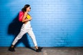 Beautiful young hipster girl goes near urban blue wall background in yellow swimsuit. Royalty Free Stock Photo