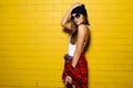 Beautiful young hipster girl posing and smiling near urban yellow wall background in sunglasses. Royalty Free Stock Photo