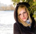 Beautiful young mysterious woman in hood on his head standing in the forest near the oil in a frosty bright day