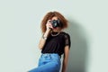 Beautiful young woman in jeans with a camera in the hands of curly hair in the Studio Royalty Free Stock Photo