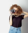 Beautiful young woman in jeans with a camera in the hands of curly hair in the Studio Royalty Free Stock Photo