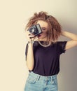 Beautiful young woman in jeans with a camera in the hands of curly hair in the Studio, retro filter Royalty Free Stock Photo