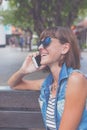 Beautiful young woman using smartphone sitting on a bench in the park. Bali island, Indonesia. Royalty Free Stock Photo