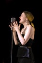 Beautiful young singer in black dress with a vintage microphone Royalty Free Stock Photo