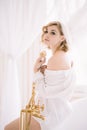 Beautiful young slender girl in a shirt in the morning in a bright room next to a white bath with gold fittings Royalty Free Stock Photo