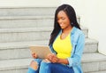 Beautiful young smiling african woman using tablet pc computer sitting in city Royalty Free Stock Photo