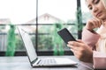 Beautiful young smiling asian muslim woman working on phone sitting in living room at home. Royalty Free Stock Photo