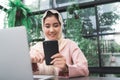 Beautiful young smiling asian muslim woman working on phone sitting in living room at home. Royalty Free Stock Photo