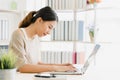 Beautiful young smiling asian woman working laptop on desk in living room at home. Royalty Free Stock Photo