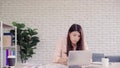 Beautiful young smiling asian woman working laptop on desk in living room at home. Asia business woman writing notebook document Royalty Free Stock Photo