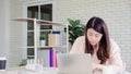 Beautiful young smiling asian woman working laptop on desk in living room at home. Asia business woman writing notebook document Royalty Free Stock Photo
