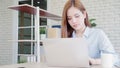 Beautiful young smiling asian woman working laptop on desk in living room at home. Asia business woman writing notebook document Royalty Free Stock Photo