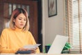 Beautiful young smiling asian woman working laptop on desk in living room at home. Royalty Free Stock Photo