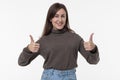 beautiful young smiling brunette dressed in casual clothes shows thumbs up