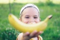 Beautiful young smiling Caucasian boy in cap with banana smile on nature background.