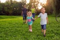 Beautiful young children walking with parents in park