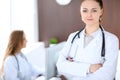 Beautiful young smiling female doctor standing in a hospital with her colleague in the background Royalty Free Stock Photo