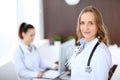 Beautiful young smiling female doctor standing in a hospital with her colleague in the background Royalty Free Stock Photo