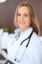 Beautiful young smiling female doctor standing in a hospital with her colleague in the background Royalty Free Stock Photo