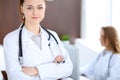 Beautiful young smiling female doctor standing in a hospital with her colleague in the background Royalty Free Stock Photo