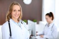 Beautiful young smiling female doctor standing in a hospital with her colleague in the background Royalty Free Stock Photo