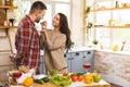 Beautiful young smiling happy couple is talking and smiling while cooking healthy food in kitchen at home Royalty Free Stock Photo