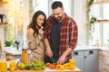 Beautiful young smiling happy couple is talking and smiling while cooking healthy food in kitchen at home Royalty Free Stock Photo