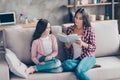 Beautiful young smiling happy mummy is holding a book and reading a fairy tale to her cute joyful daughter, they are sitting on