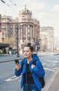 Beautiful young smiling tourist woman with mobile phone and backpack near road in the Belgrade city, Serbia Royalty Free Stock Photo